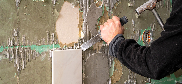 Professionnel qui retire du carrelage mural